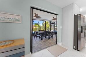 A modern kitchen with a built-in refrigerator, a dining area with a table and chairs, and a view of a swimming pool through a glass door. - Waterfront Heated Pool | 10 Min to Anna Maria (Bradenton)