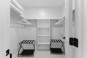 Ein begehbarer Kleiderschrank mit zwei Metallregalen, Ablagen und einer Tür.