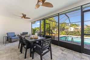 A spacious patio with a dining table, chairs, and a view of a swimming pool. - Waterfront Heated Pool | 10 Min to Anna Maria (Bradenton)