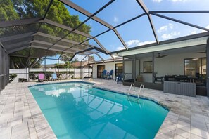 A covered swimming pool with a patio area, chairs, and a table. - Waterfront Heated Pool | 10 Min to Anna Maria (Bradenton)