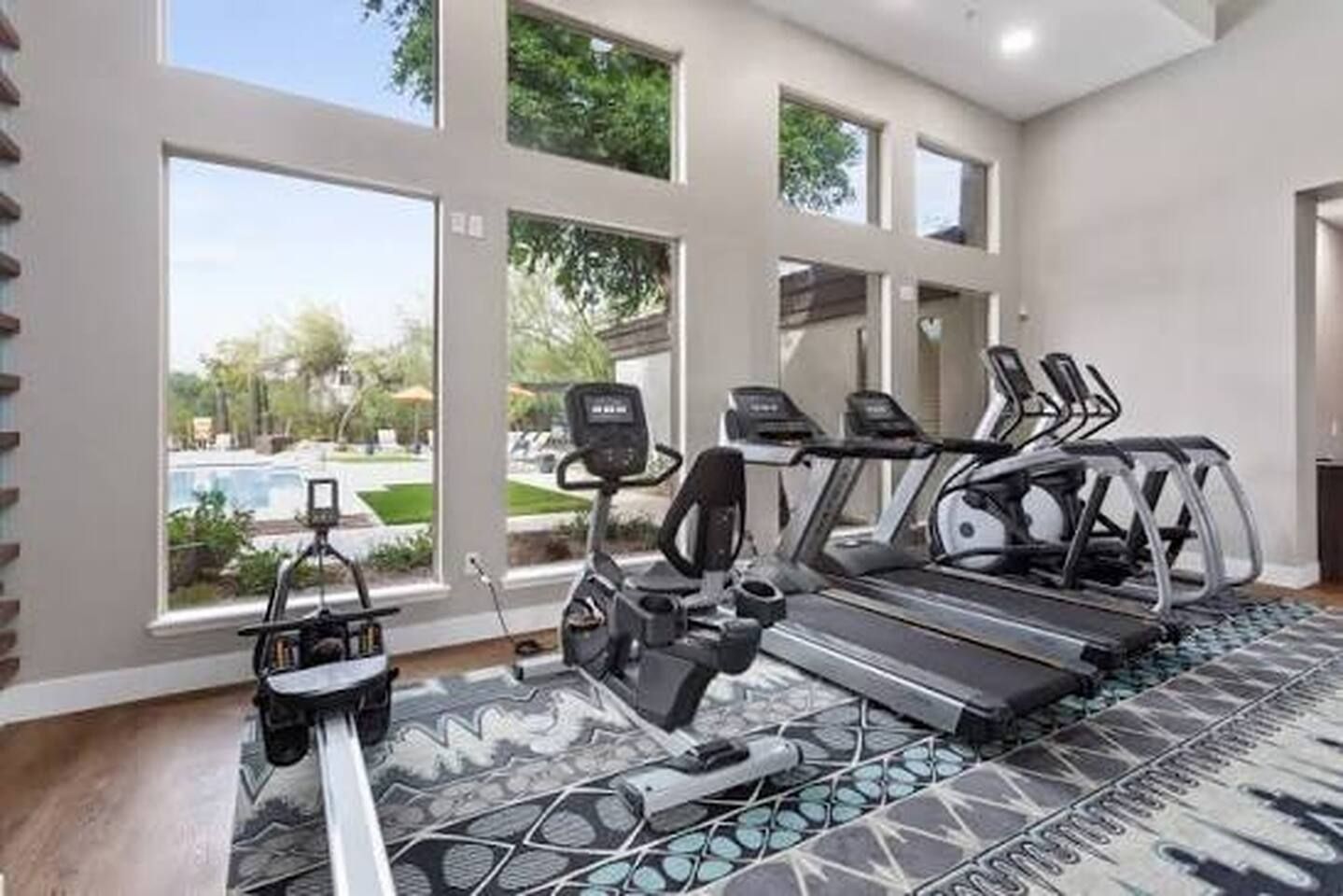 Une salle de sport équipée de tapis de course, d’un vélo d’appartement et d’un appareil d’aviron.