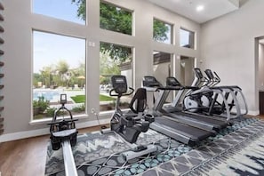 Ein Fitnessraum mit Laufbändern, Fahrrädern und einem Rudergerät.