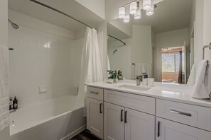 Un baño moderno con cabina de ducha, un espejo grande y tocador con lavabo.