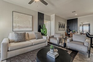 Ein modernes Wohnzimmer mit Sofa, Sesseln, Couchtisch und Essbereich mit Blick.