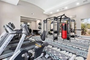Un gimnasio en casa con cintas de correr, una estación de pesas y un saco de boxeo.