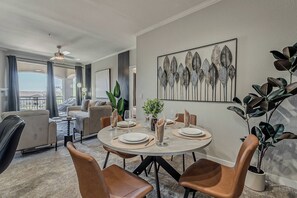 Un comedor con una mesa redonda preparada para cuatro personas, rodeada de sillas de cuero.