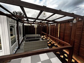 A covered outdoor area with a pergola structure, seating, and a small table. - 3-Bed Bungalow near Elizabeth Line • Parking • Windsor (Slough)