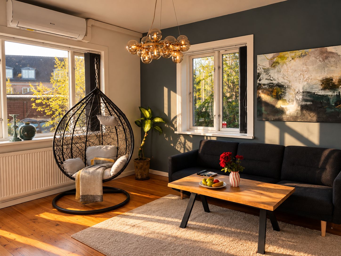 A living room with a round hanging chair, a black sofa, a wooden coffee table, and a large window with a view of trees.