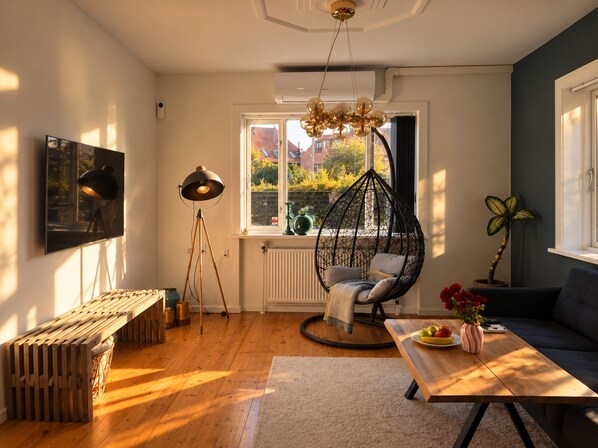 A modern living room with a hanging chair, a wooden bench, a table with fruit, and a view of the outside. - Charming Private Apartment in the Heart of København (Copenhagen)