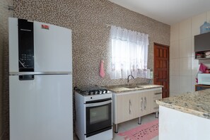 Eine Küche mit Kühlschrank, Herd, Spüle und Holzschränken.