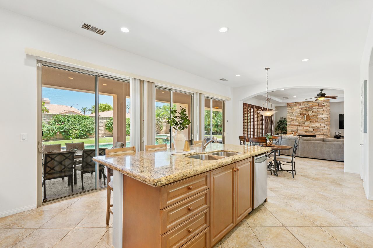 A spacious kitchen with a large island, sliding glass doors leading to an outdoor patio, and a stone accent wall.