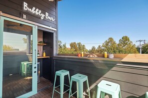 An outdoor seating area with a bar named 'Bubble Bar', featuring two stools and a wooden counter with a glass enclosure. - The Jolene Bubbly Bar with Views 5min to DT (Nashville)