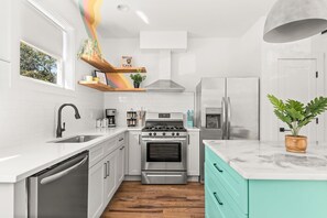 A modern kitchen with white cabinetry, a stainless steel stove, and a teal countertop. - The Jolene Bubbly Bar with Views 5min to DT (Nashville)