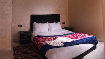 A bedroom with a bed, a nightstand, a rug, and a wall-mounted light.