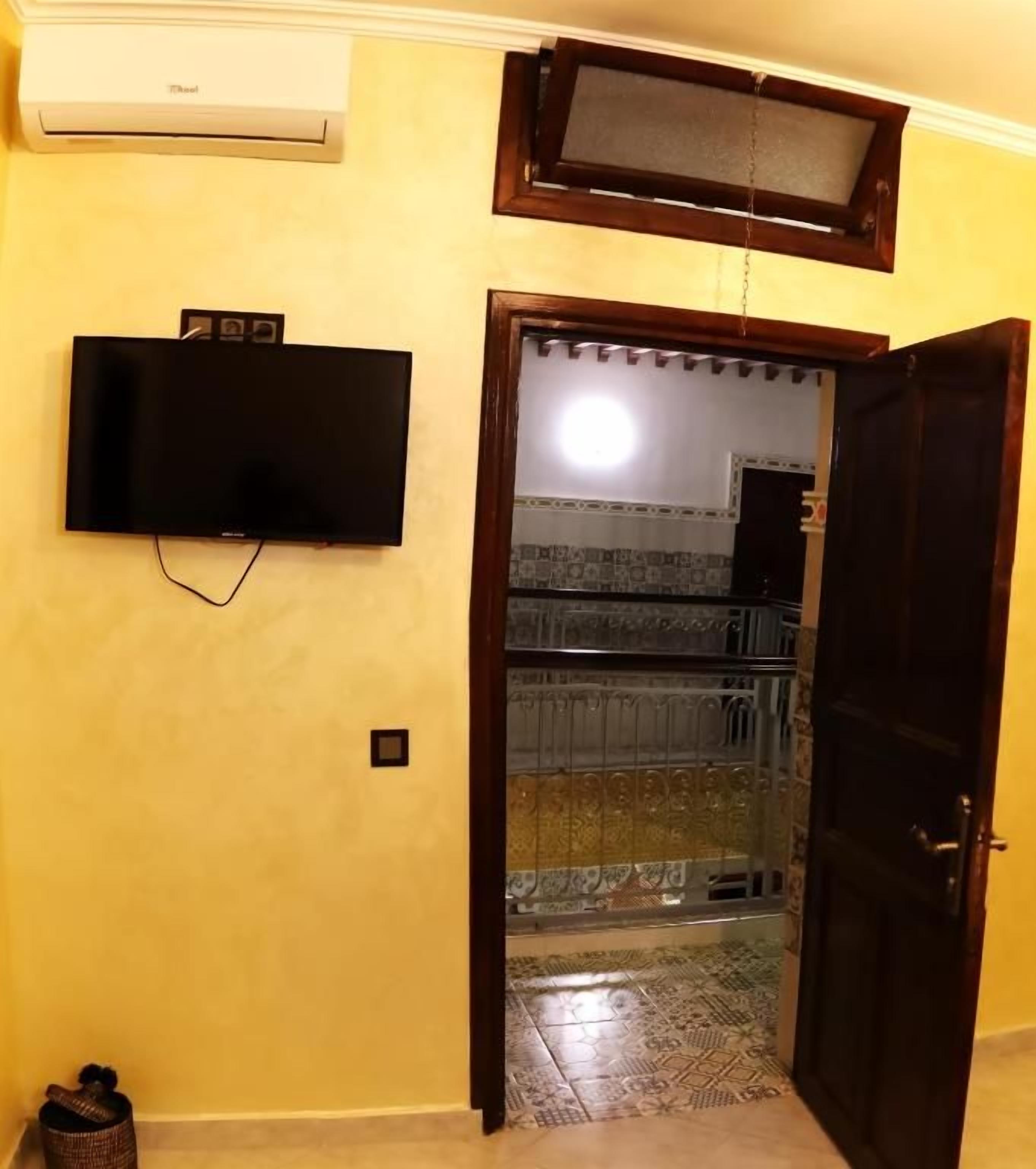 Una habitación con televisión montada en la pared, una puerta que da a un balcón y un suelo con diseño.