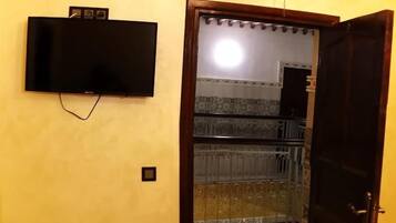 Una habitación con televisión montada en la pared, una puerta que da a un balcón y un suelo con diseño.