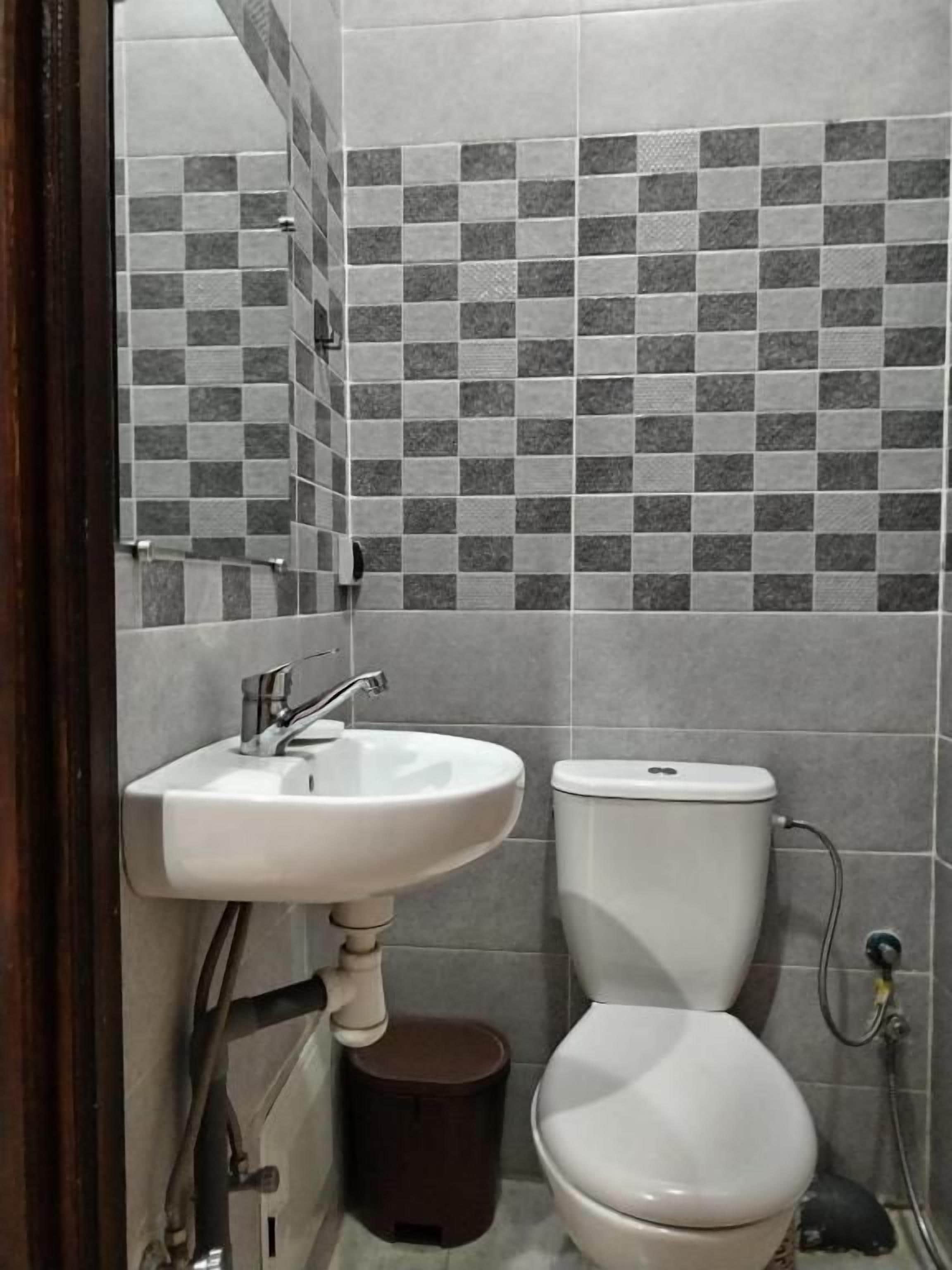 Un baño con lavamanos blanco, inodoro y pared con azulejos.