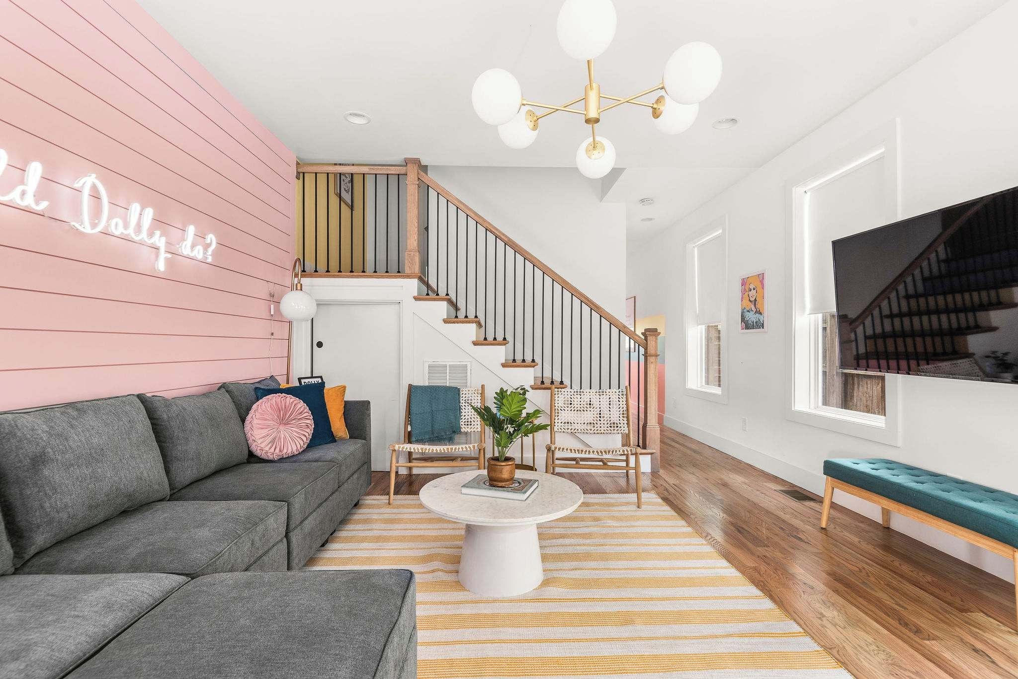 A modern living room with a grey sofa, a round coffee table, and a staircase with wooden railings.
