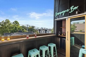 Eine Dachterrasse mit einer Neonreklame, Sitzgelegenheiten im Freien und Blick auf die Skyline.