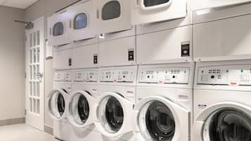 A row of stacked front-loading washing machines in a commercial laundry facility.