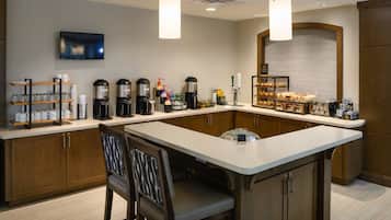 A modern kitchen with a central island, coffee makers, a TV, and a breakfast bar.