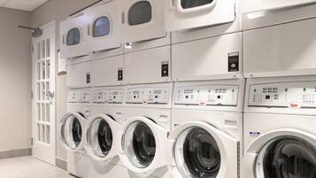 A row of stacked front-loading washing machines in a commercial laundry facility.