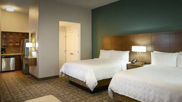 A hotel room with two beds, a kitchenette, and a bathroom.