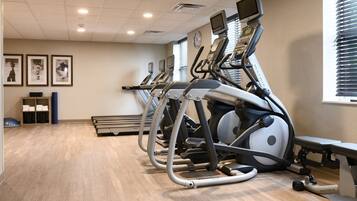 A gym with multiple treadmills, a bench, and a wall clock.