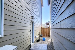 A narrow outdoor space with wooden siding, a metal gate, a blue trash bin, and a small concrete step leading to a door. - *2 Bedrooms|Full Kitchen|Faces Park (Calgary)