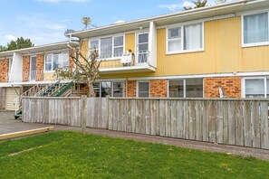 A two-story residential building with a wooden fence, a visible staircase, and a small tree in the yard. - Sandringham 2BR Haven near Eden Park with Air-con (Auckland Central Suburbs)