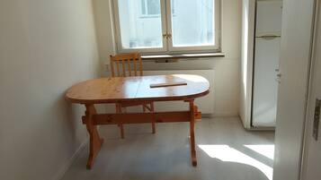 A room with a wooden table and chairs, a window with a view, and a white door.