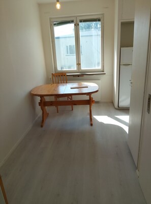 A room with a wooden table and chairs, a window with a view, and a white door. - Vrbo Property (fagesta)
