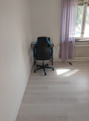 A room with a black office chair, a window with a curtain, and a radiator. - Vrbo Property (fagesta)