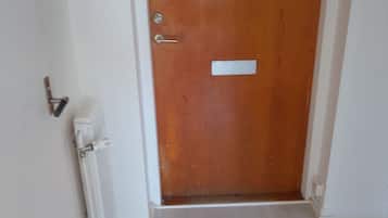A closed wooden door with a keyhole, a handle, and a small rectangular label.