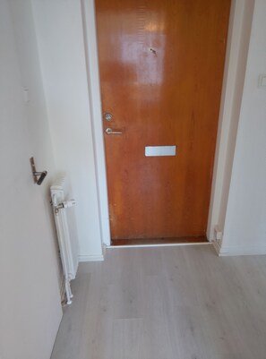 Una porta de fusta tancada amb un ull de claus, un pom i una petita placa rectangular.