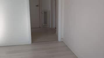 A hallway with a radiator, a door, and a light switch on the wall.