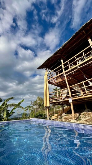 A swimming pool with a clear blue sky and clouds in the background.