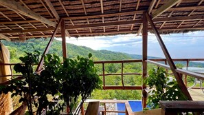 A wooden structure with a thatched roof overlooking a lush landscape.