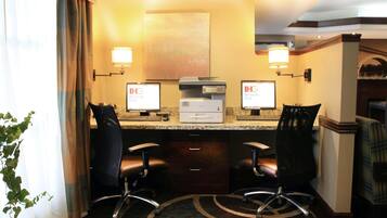 A hotel room with two computer desks, two chairs, a printer, and a large mirror on the wall.