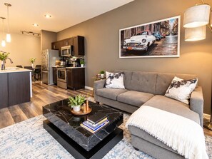 A modern living room with a sofa, a coffee table, and a kitchen in the background. - The little Havana (Austin)