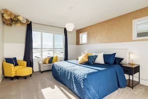 A hotel room with a large bed, a sofa, a nightstand, and a view of the beach. - ~PrivateFencedYard|2FamilyRms|ParkNear|BlueBeauty (Calgary)