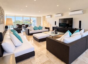Ein modernes Wohnzimmer mit einer Sofagarnitur, einem Couchtisch und einem Flachbildfernseher.
