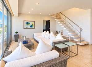 A modern living room with a sofa, coffee table, and a staircase. - Luxury Penthouse-Private Jacuzzi -8-BR (Playa del Carmen)