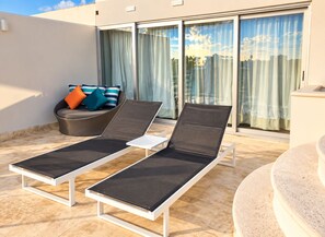 A sunlit outdoor seating area with two lounge chairs and a cushioned sofa with pillows. - Luxury Penthouse-Private Jacuzzi -8-BR (Playa del Carmen)