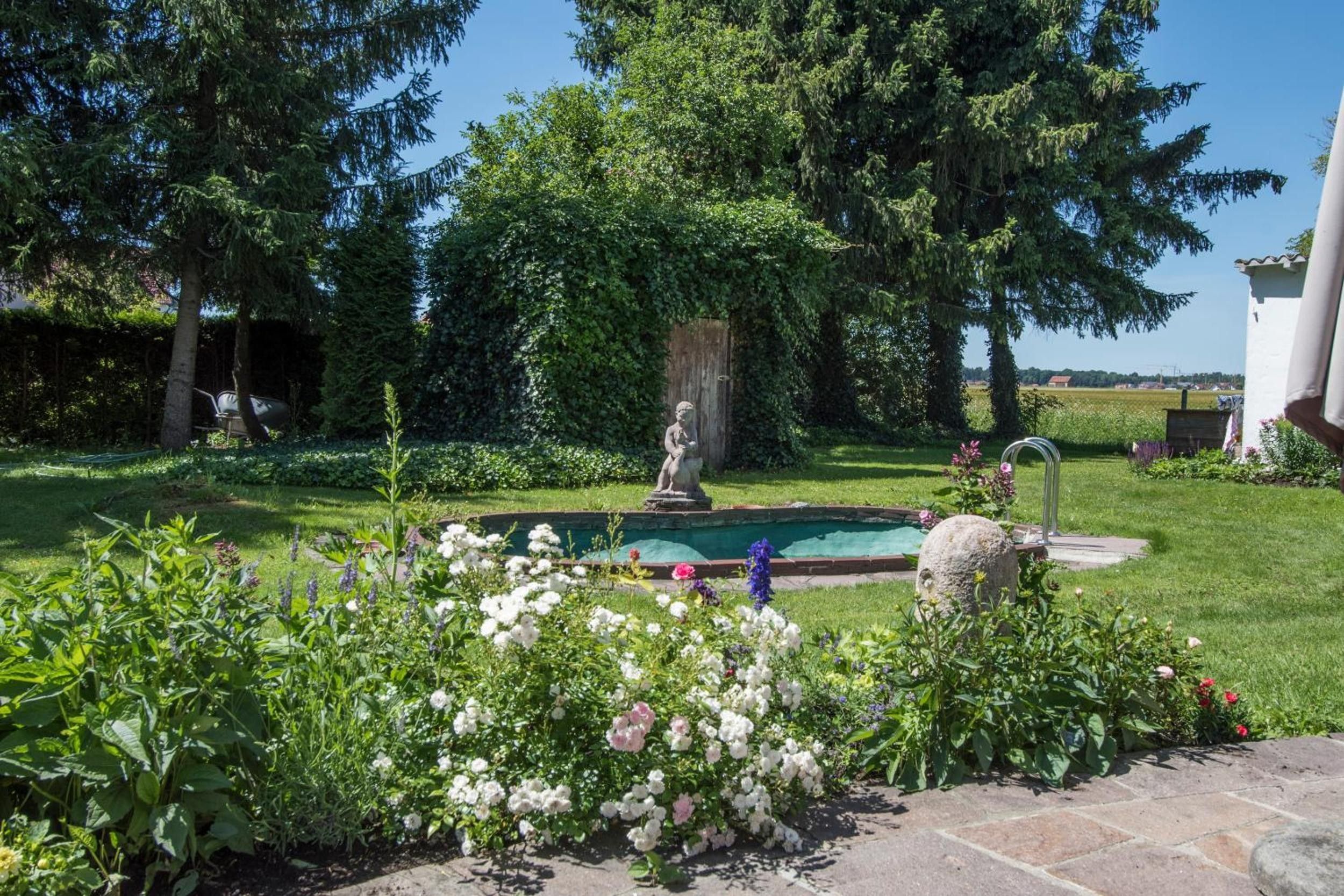 Ein Garten mit Brunnen, Statue und verschiedenen Blumen.
