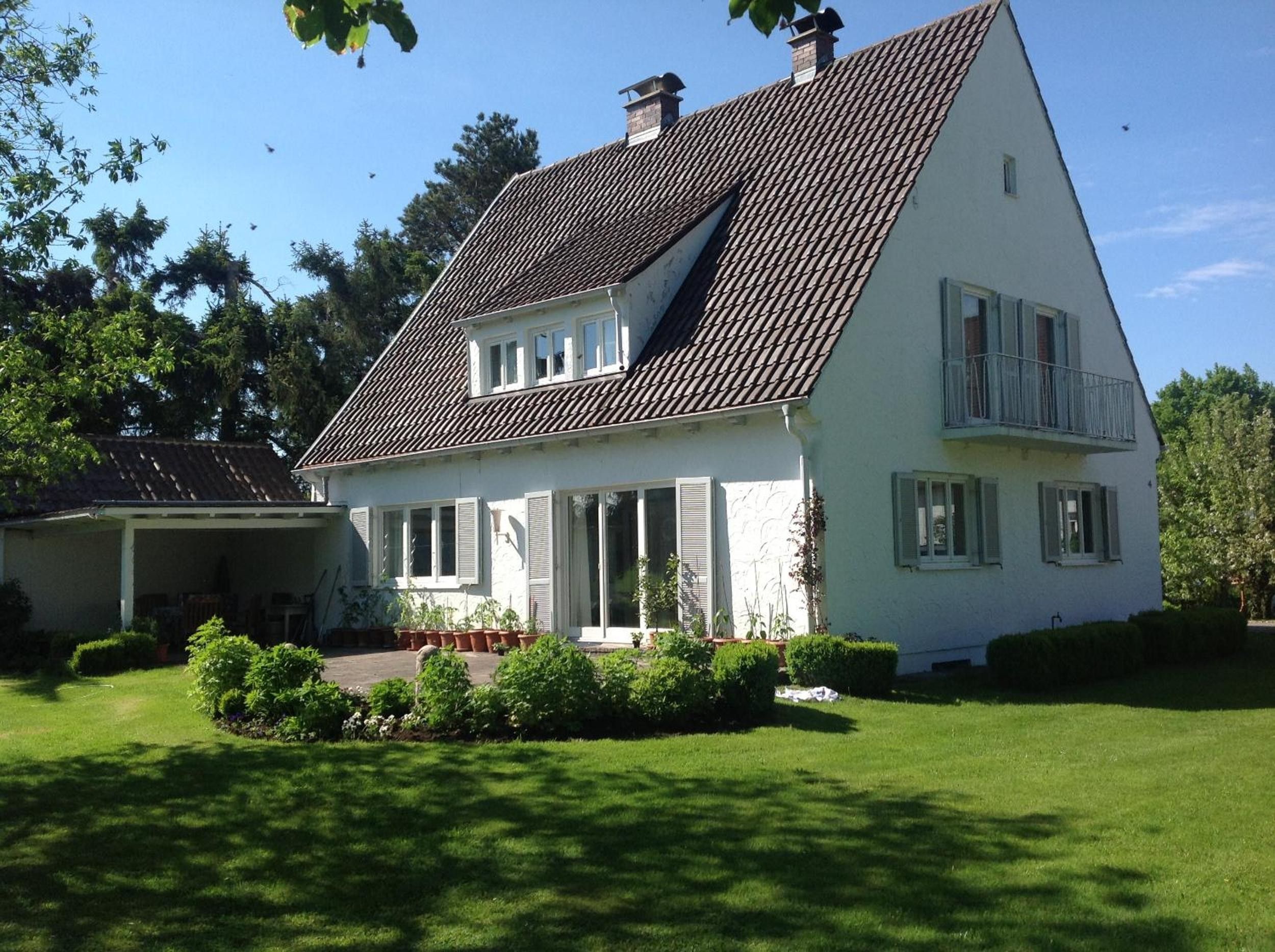 Een tweelaags huis met een schuin dak, een overdekte veranda en een verzorgd gazon.