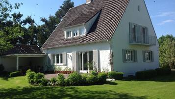 Een tweelaags huis met een schuin dak, een overdekte veranda en een verzorgd gazon.
