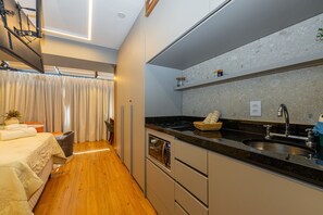 A modern kitchen with a black countertop, stainless steel appliances, and a built-in oven. - Studio with Pool and Gym 400m from Paulista Avenue (São Paulo)