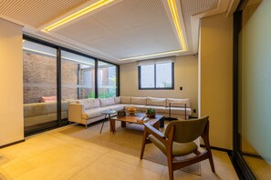 Un salon moderne avec un canapé d’angle, une table basse et une chaise en bois.