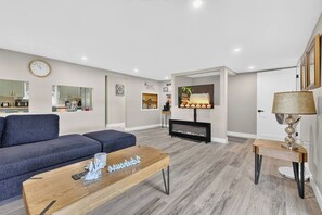 Ein modernes Wohnzimmer mit Sofa, Couchtisch, Kamin, Fernseher und einer Wanduhr.